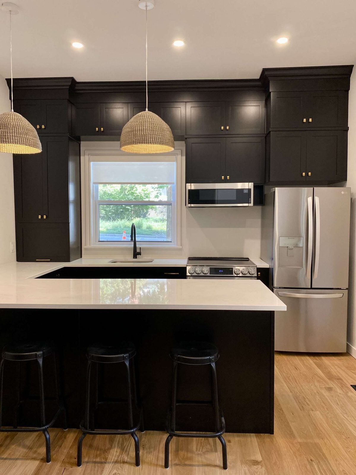 Dark modern kitchen renovation with island and bar stools