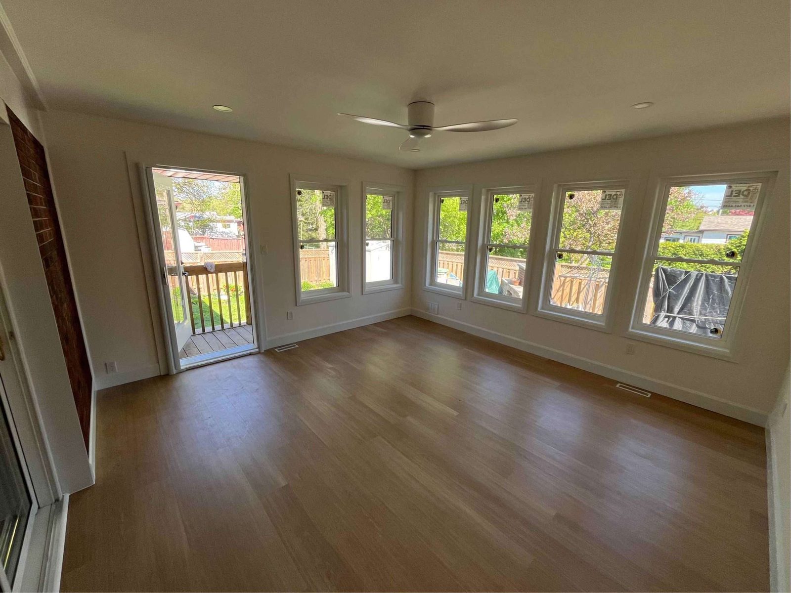 Bright sunroom addition with wall of windows and wood floor