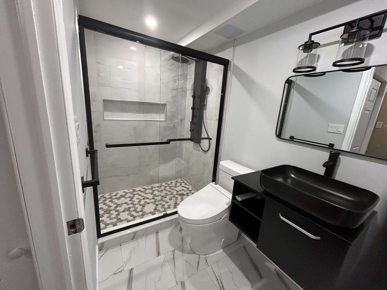 Warm renovated kitchen with wood floors and black appliances by Malamar Construction